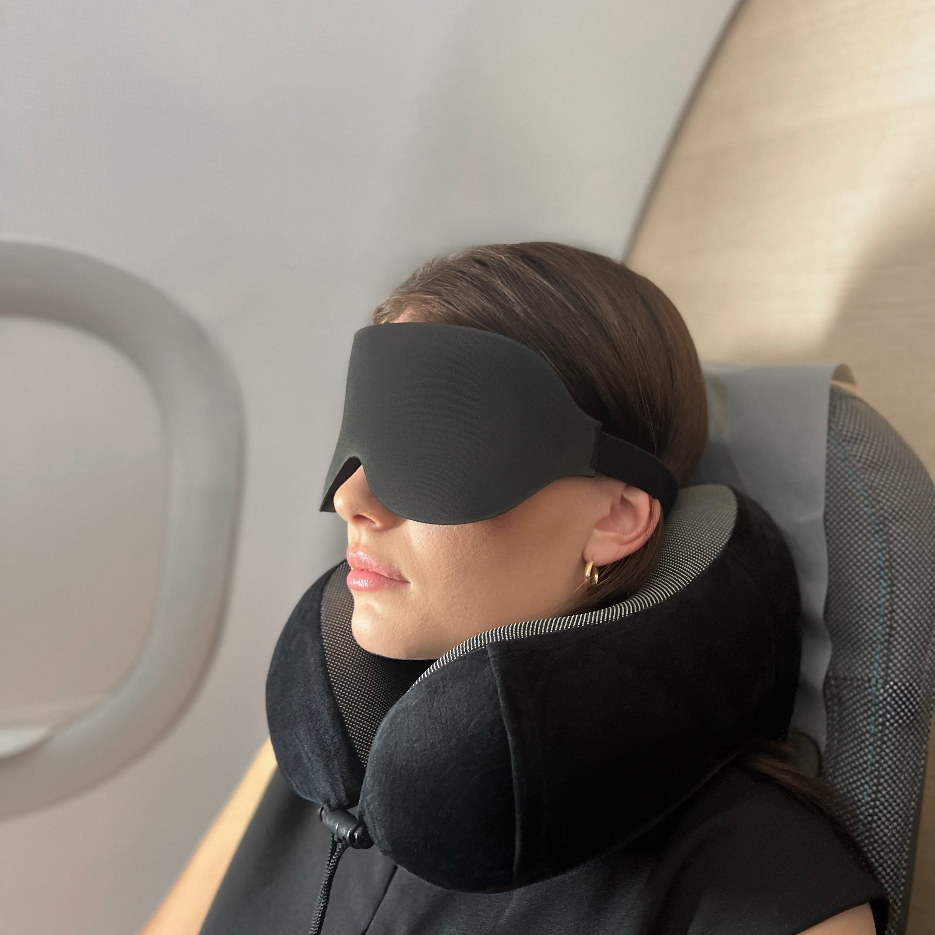 Person som hviler på fly med norzen sovemaske og reisepute